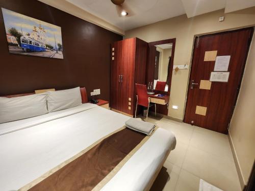 a bedroom with a bed and a desk in it at Hotel Saad in Kolkata