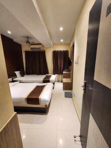 a hotel room with two beds and a door at Hotel Saad in Kolkata