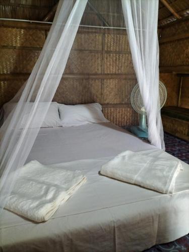 a bed with white sheets and a mosquito net at Lanta Rabbit Rooms in Ko Lanta