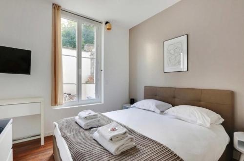 une chambre avec un lit avec des serviettes dessus dans l'établissement Magnifique 2 pièces, clair neuf, à Paris
