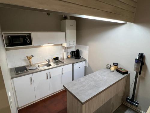 - une petite cuisine avec des placards blancs et un comptoir dans l'établissement L'essentiel, studio tout équipé, à Roanne