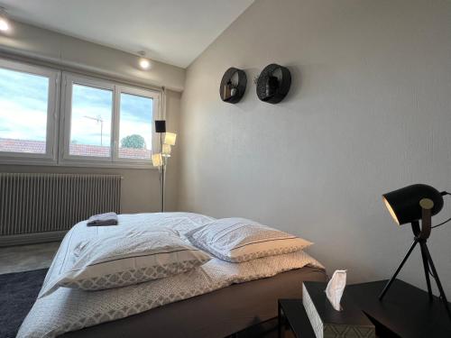 une chambre blanche avec un lit et une fenêtre dans l'établissement L'essentiel, studio tout équipé, à Roanne