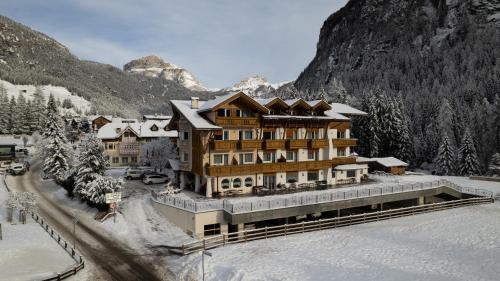 a ski lodge in the mountains with snow on the ground at Alpenhotel Panorama in Campitello di Fassa