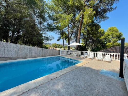 a swimming pool with chairs and an umbrella next to a fence at Chalet El Tochar in Valencia