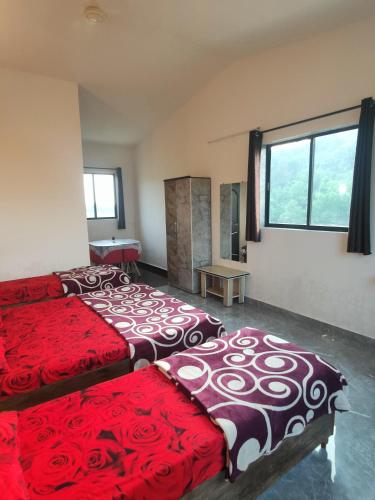 a bedroom with two beds with red and white covers at Shobha Farmhouse in Kashid