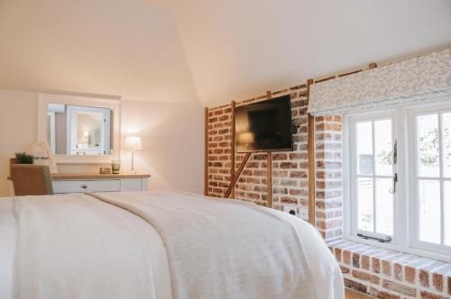 a bedroom with a bed and a tv on a brick wall at The Kings Arms Rooms in Canterbury