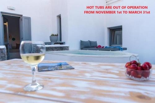 a glass of wine sitting on a table with a bowl of apples at LAGADI SUITES by K&K in Mesaria