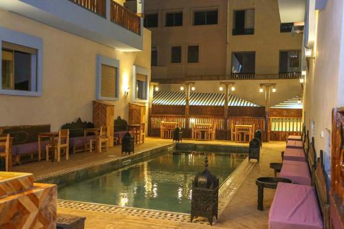 a swimming pool in a building with tables and chairs at Imsouane WOOD HOUSE in Imsouane