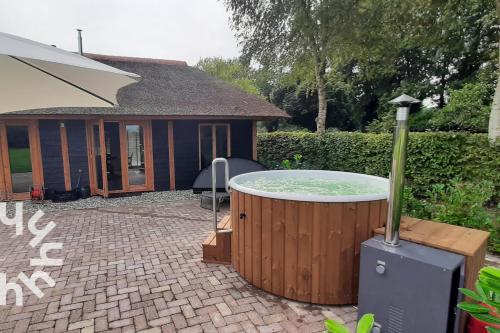 a hot tub in a yard next to a house at OV575 - Landelijk gelegen 2P vakantiehuis met hottub in Sint-Jansklooster in Sint Jansklooster