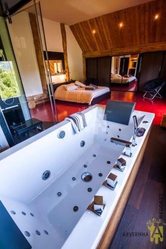 - une grande baignoire blanche dans une chambre avec un lit dans l'établissement La Fuste du Lac, à Chambon-sur-Lac