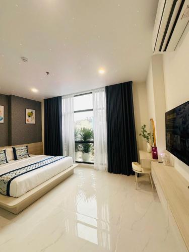 a bedroom with a large bed and a large window at The Luxury Hotel in Ho Chi Minh City