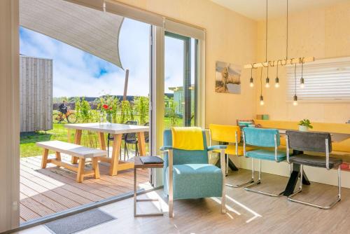 a dining room with a table and chairs and a window at Lucky Bay - Ecohuisjes Terschelling in Midsland