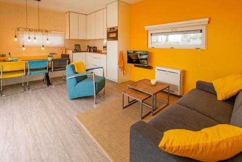 a living room with a couch and a table and a kitchen at Lucky Bay - Ecohuisjes Terschelling in Midsland