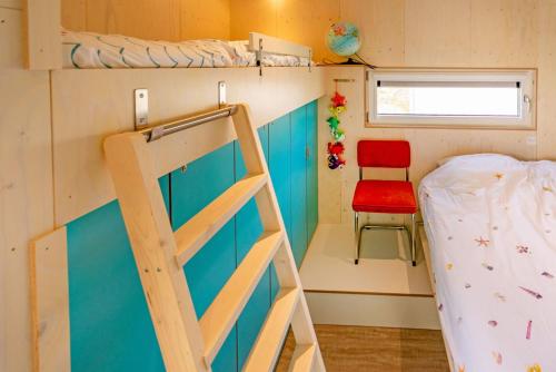 a tiny house with a bunk bed and a chair at Lucky Bay - Ecohuisjes Terschelling in Midsland