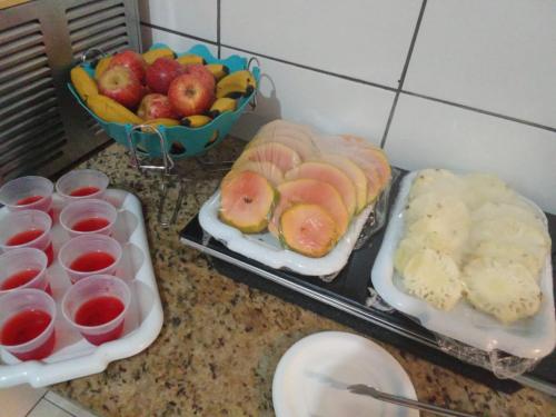 a counter with two trays of food and a bowl of fruit at Pousada Vila Pitanga in Santos