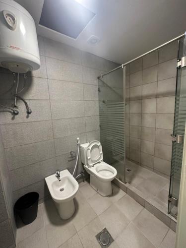 a bathroom with a toilet and a shower and a sink at central apartment for rent 19 in Umm Uthainah