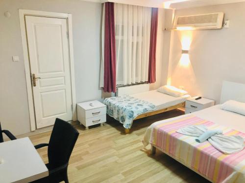 a room with two beds and a table with a desk at Gold in Confort hotel in Barbaros