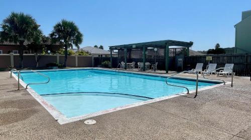 a large swimming pool with chairs and a gazebo at Cozy Coastal Repose in Padre Island