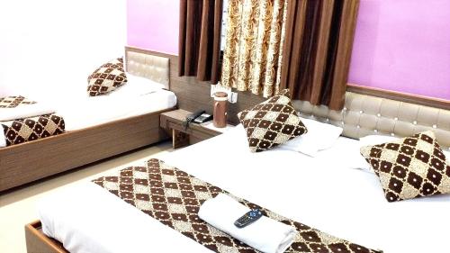 two beds in a hotel room with a mirror at Sai Balaji Residency in Shirdi