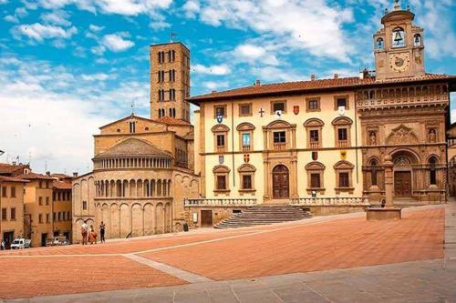 a large building with a clock tower and a building with a staircase at A'Loro B&B in Terranuova Bracciolini