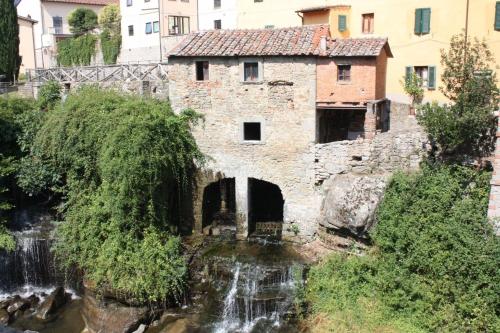 an old building next to a river with a waterfall at A'Loro B&B in Terranuova Bracciolini