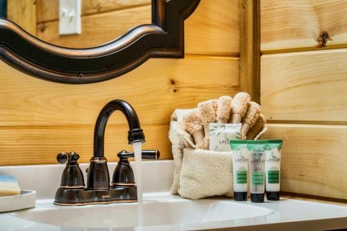 Eine Badezimmerablage mit Waschbecken, Handtüchern und Wasserhahn in der Unterkunft Romantic Cabin - The Woodland Nook in Sevierville
