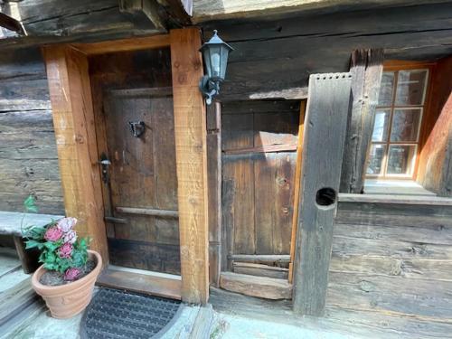 a wooden house with a door and a potted plant at Mazot JHR Unterbäch VS in Bachtolen
