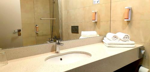 a bathroom with a sink and a mirror and towels at Hotel Tennis Club in Prostějov