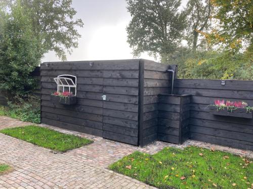 a black fence with a window and flowers on it at B&B de Perenboom in Eck en Wiel
