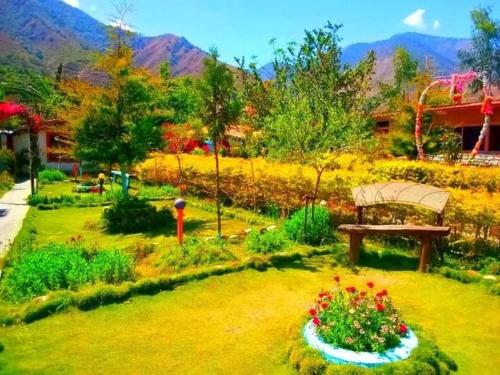 un parque con un banco y flores en el césped en Olive Eco Village Hotel, en Pārtol