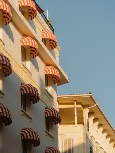- une façade d'un bâtiment avec des balcons rouges et blancs dans l'établissement Edgar Suites Cannes - Rue d'Antibes, à Cannes