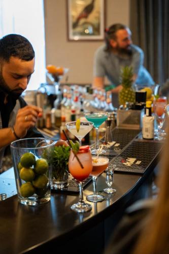 a man sitting at a bar with a table full of drinks at Queens Hotel & Spa Bournemouth in Bournemouth