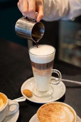 a person pouring coffee into a cup on a table at Queens Hotel & Spa Bournemouth in Bournemouth