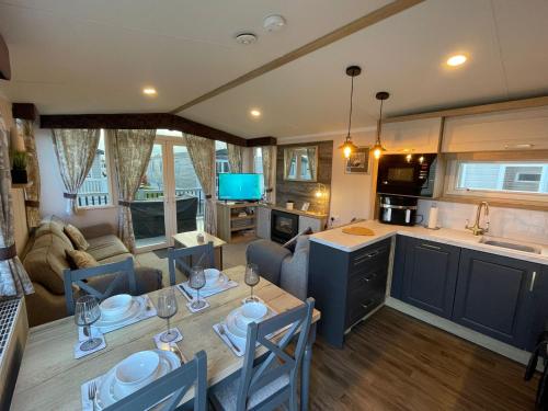 a kitchen and living room with a table and a couch at Golden Palm Resort - Bordeaux Deluxe - Coastal Caravan Breaks in Chapel Saint Leonards