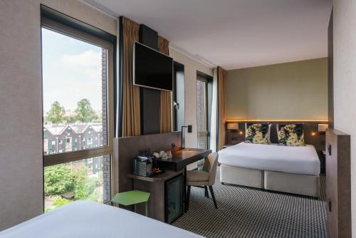 een hotelkamer met een bed, een bureau en een raam bij Monet Garden Hotel Amsterdam in Amsterdam