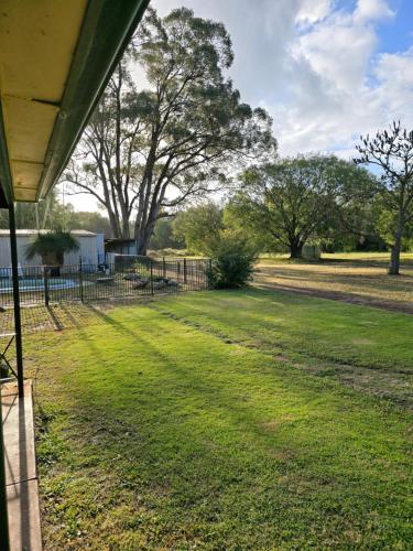 a yard with a fence and trees in the background at Tuhearts Family Stay in Wonnerup