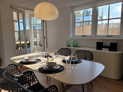 a dining room with a white table and chairs at Vakantiehuis de Zeeuwse Zonnehoed in Serooskerke