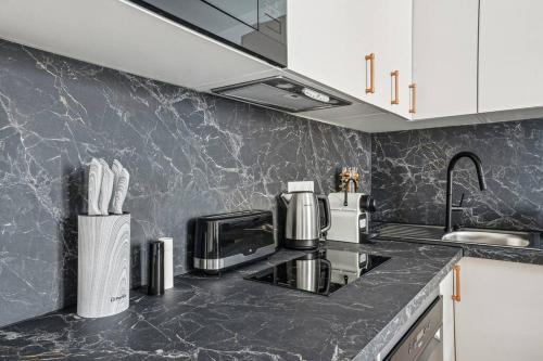 - une cuisine avec des comptoirs en marbre noir et des armoires blanches dans l'établissement Élégant Tour Eiffel, à Paris