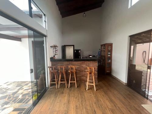 a kitchen with two stools and a bar in a room at Casa aconchegante-lazer completo in Três Pontas
