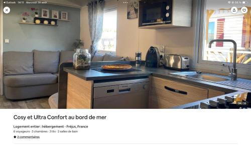a kitchen with a couch and a pizza on a counter at cosy et ultra confort au bord in Fréjus