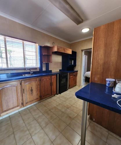 a kitchen with wooden cabinets and a blue counter top at FM GUEST LODGE Comfort, Tranquility & Peace of Mind in Johannesburg