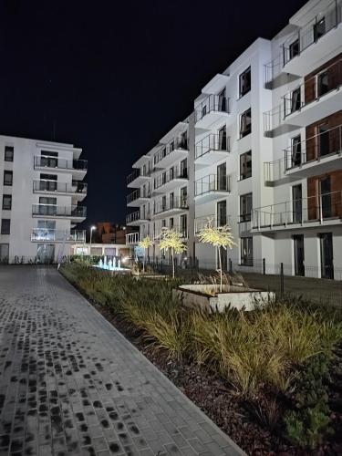two white apartment buildings at night with trees in front at Apartament w Bartoszycach in Bartoszyce