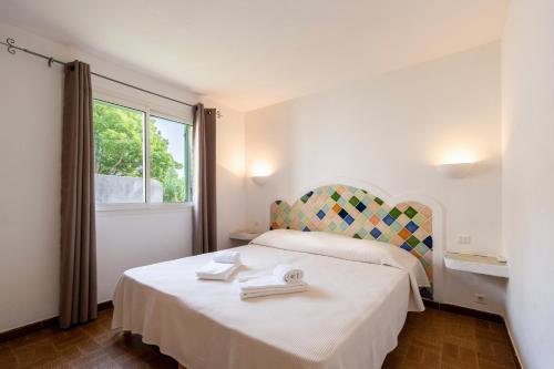 une chambre avec un lit blanc et une fenêtre dans l'établissement Résidence Domaine De Caranella, à Porto-Vecchio