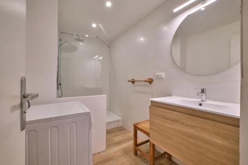 une salle de bain blanche avec un lavabo et un miroir dans l'établissement Olympe - Les 2 Alpes, à Les Deux Alpes