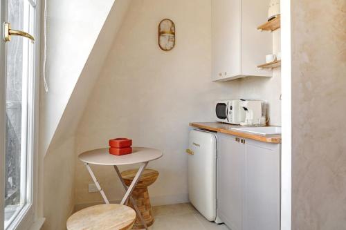 - une petite cuisine avec une petite table à côté d'un réfrigérateur dans l'établissement La vue du Marais, à Paris