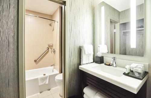 a bathroom with a sink and a toilet and a mirror at Riu Plaza Fisherman's Wharf in San Francisco