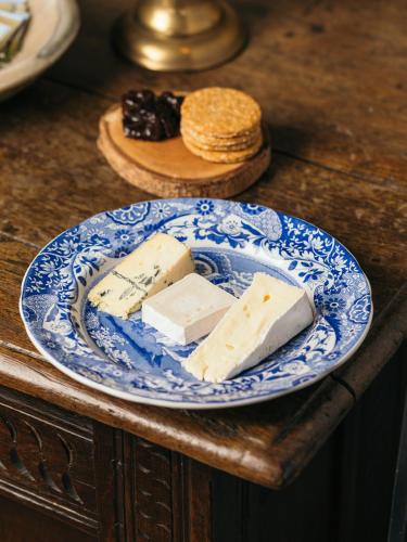 a blue and white plate of cheese on a table at Nest Farmhouse in Docking