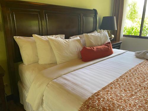 a bedroom with a large bed with two red pillows at Hotel Boutique Casona del Cafetal and Lakeside Restaurant in Cachí