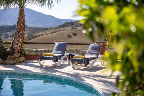 two chairs and a table next to a swimming pool at Finca Gran Cerros in Alora