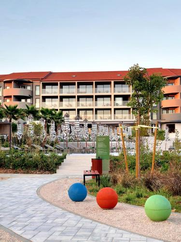 a building with a park with colorful balls in front of it at Molum Hotel & Residences in Sveti Filip i Jakov